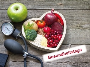 herzförmige Schale mit verschiedenem Obst neben einer Blutdruckmanschette auf Holzhintergrund